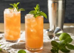 Zombie koktail - aj z Deadhead rumu, pohár s oranžovým nápojom a ľadom, ozdobený mätou