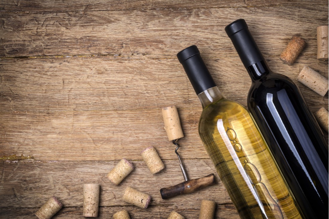 Víno a kalórie - biele a červené víno so zátkami-korkom a vývrtkou na stole