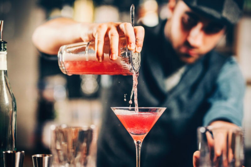 Cosmopolitan koktail, barman nalieva do pohára na Martini