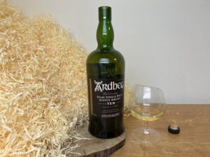 Ardbeg 10 y - fľaša, alkohol v pohári a korkový štupeľ vedľa