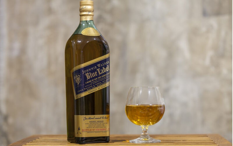 Johnnie Walker Blue Label - fľaša a pohárik s whisky na stole
