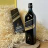 Johnnie Walker Double Black - celá fľaša na drevenom podnose a v pozadí kartón
