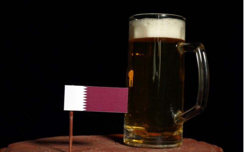 MS vo futbale Katar a pivo - katarská vlajka a pohár piva na drevenej podložke