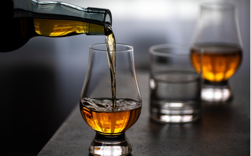 Najlepšia whisky - škótska, írska, bourbon: nalievanie whisky do degustačného pohára v tvare tulipánu 