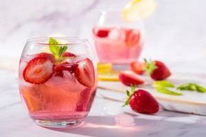 Pink gin tonic drink v pohári s ľadom a jahodami a mätou