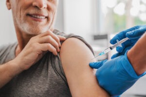 Muž počas očkovania, dostáva injekciu do ramena