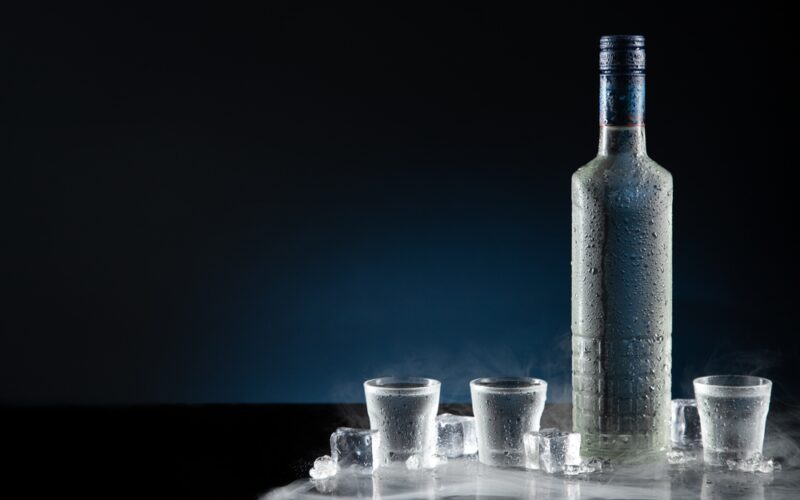 Najlepšie vodky - ilustračný obrázok: fľaša a poháriky na stole (detail)